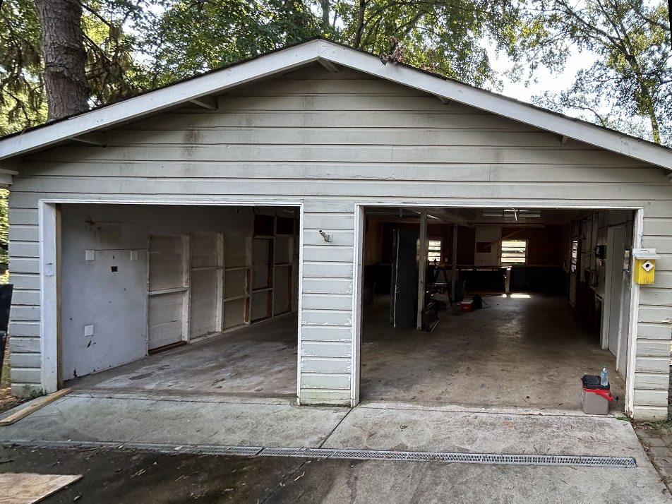 Detached two-car garage in Charlotte before the rebuild, with open bays and worn siding