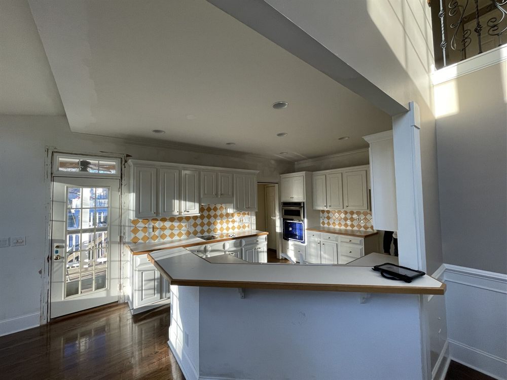 Charlotte kitchen before renovation, with painted cabinets, a peninsula and a checkerboard tile backsplash