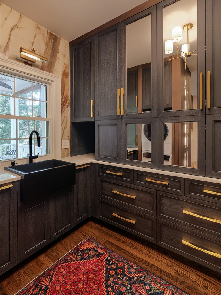 The same room rebuilt as a scullery by Revival Construction, with a black farmhouse sink and dark stained cabinetry