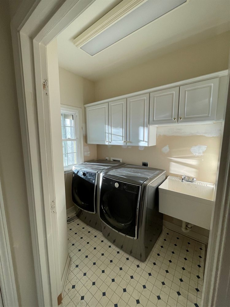 Laundry room before renovation, with a washer, dryer and utility sink under the window