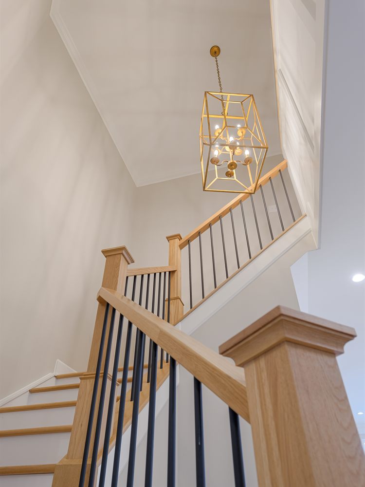 The same staircase after renovation by Revival Construction, with white oak treads, a new railing and a brass lantern