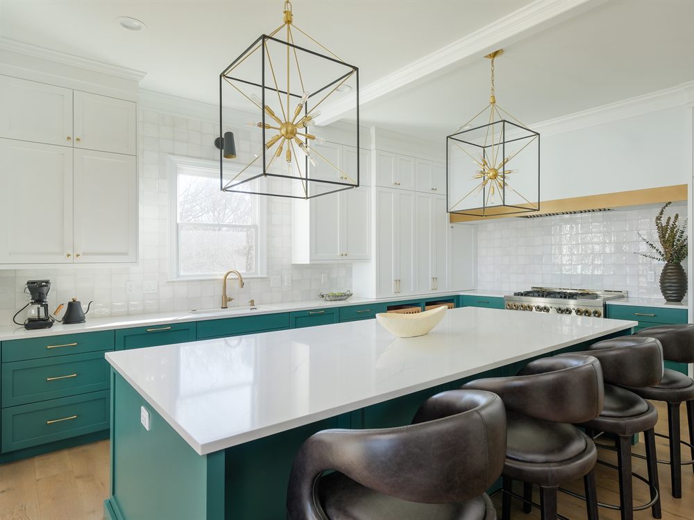 The same Lake Wylie kitchen after renovation by Revival Construction, with white cabinetry, a teal island and brass pendant lights