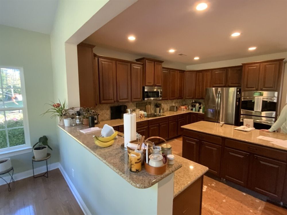 Monroe kitchen before renovation, with dark wood cabinets and a granite peninsula