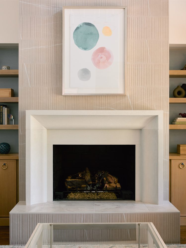 Same living room fireplace after renovation: cast stone surround and white oak floating shelves, Charlotte