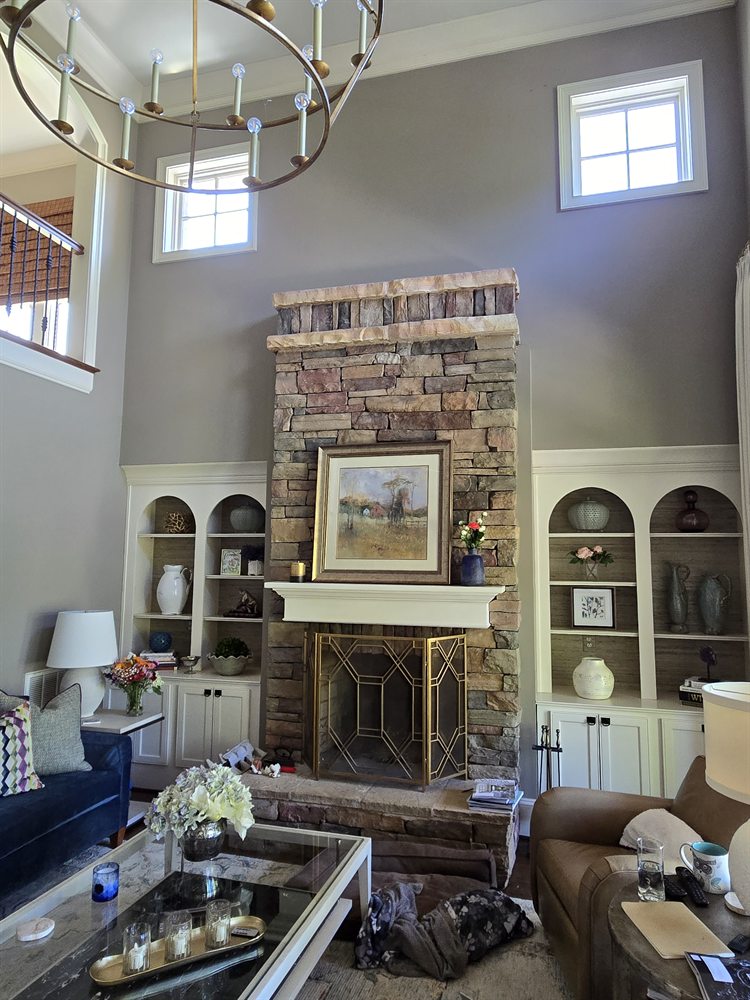 Providence Springs two-story living room before renovation, with a stacked-stone fireplace and arched built-ins