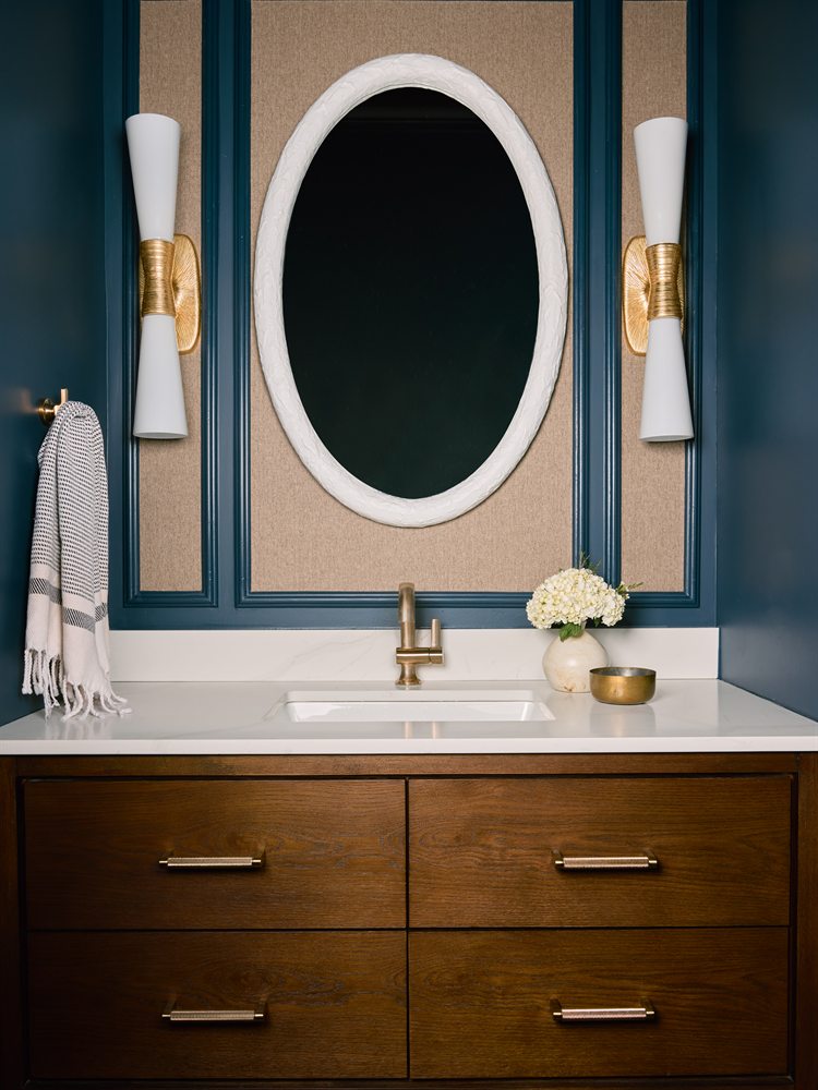 Same powder bath after renovation: floating wood vanity, oval mirror and navy panel molding, Charlotte