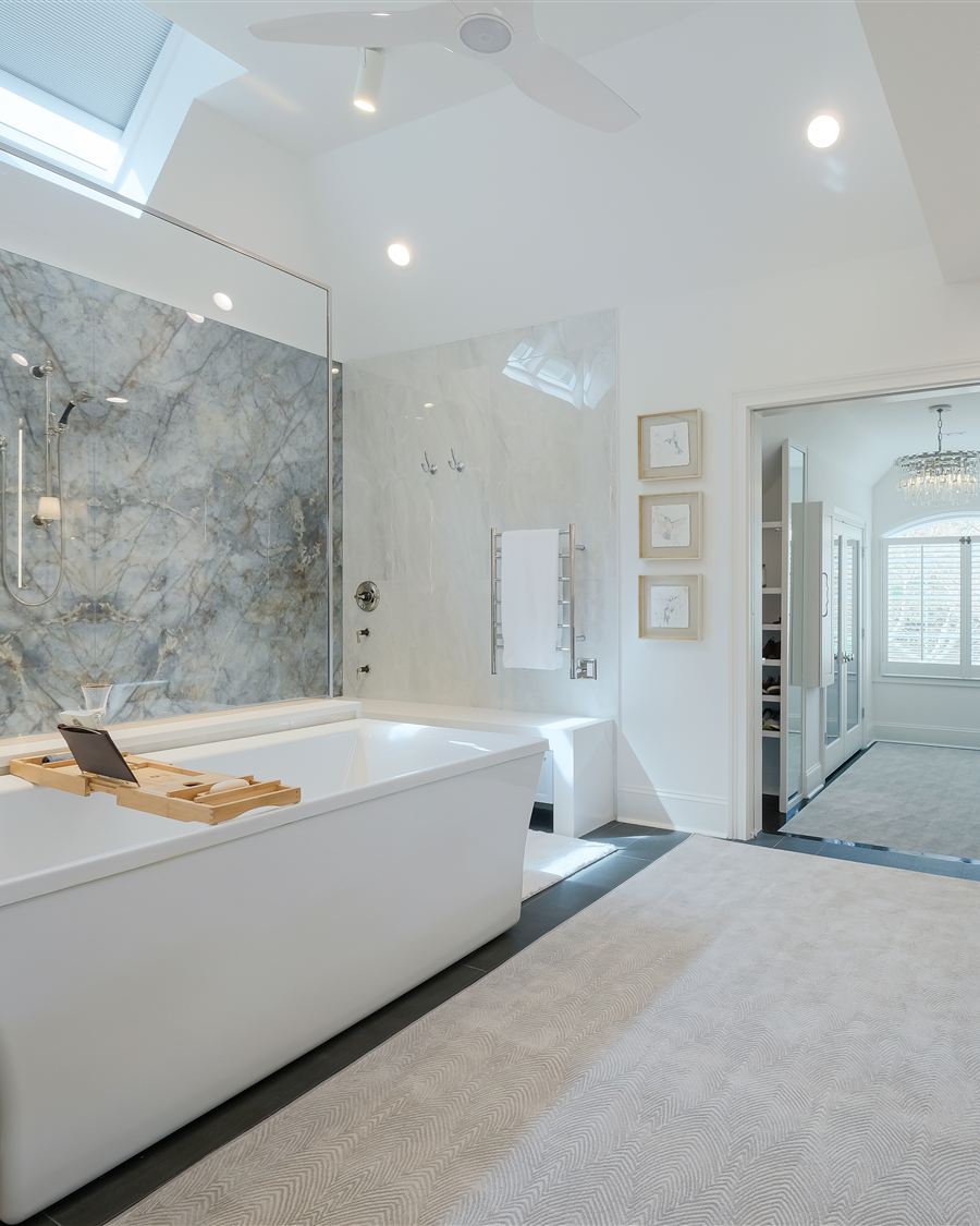 The same bathroom after renovation by Revival Construction: book-matched porcelain slab shower, freestanding soaking tub and custom inset vanities