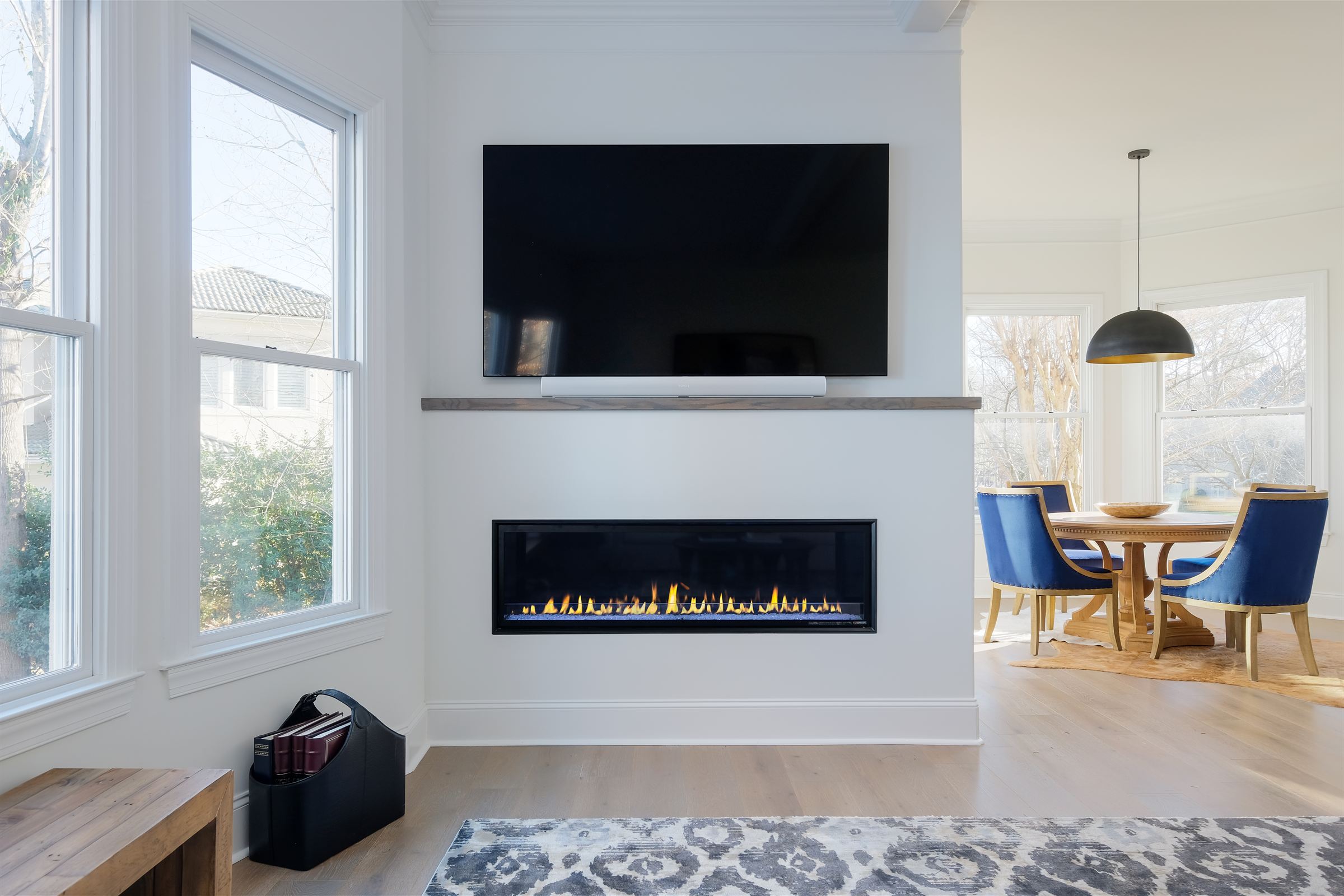 Linear fireplace wall with a white oak mantel and a sunlit dining nook in a Lake Wylie renovation by Revival Construction