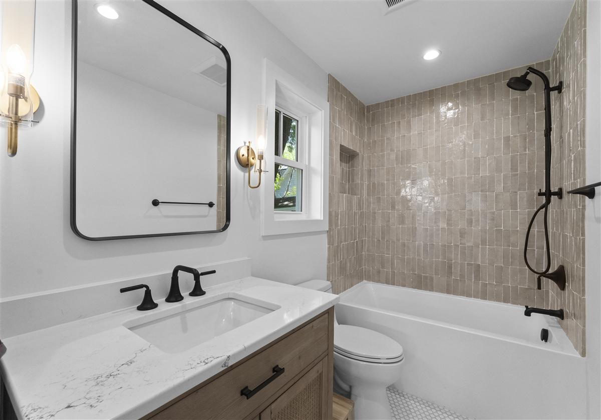 Guest studio bath with a black-framed mirror and zellige tub shower, Charlotte ADU