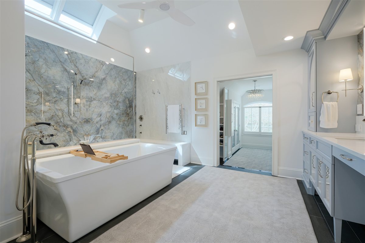 Freestanding tub under a skylight beside the porcelain slab shower, Charlotte spa bath