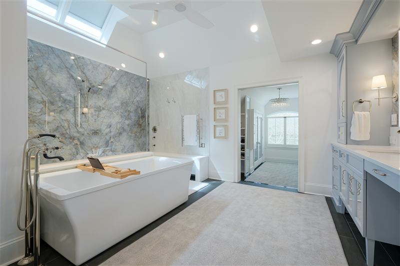 Charlotte spa primary bath by Revival Construction: book-matched porcelain slab shower and freestanding tub
