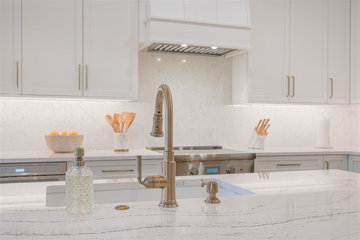 Brass faucet at a Cambria quartz island, Peninsula townhouse kitchen