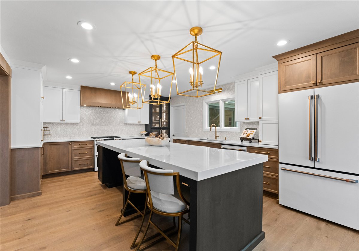 Kitchen with a dark island, brass lantern pendants and white cabinetry, River Chase lakefront renovation in Cornelius