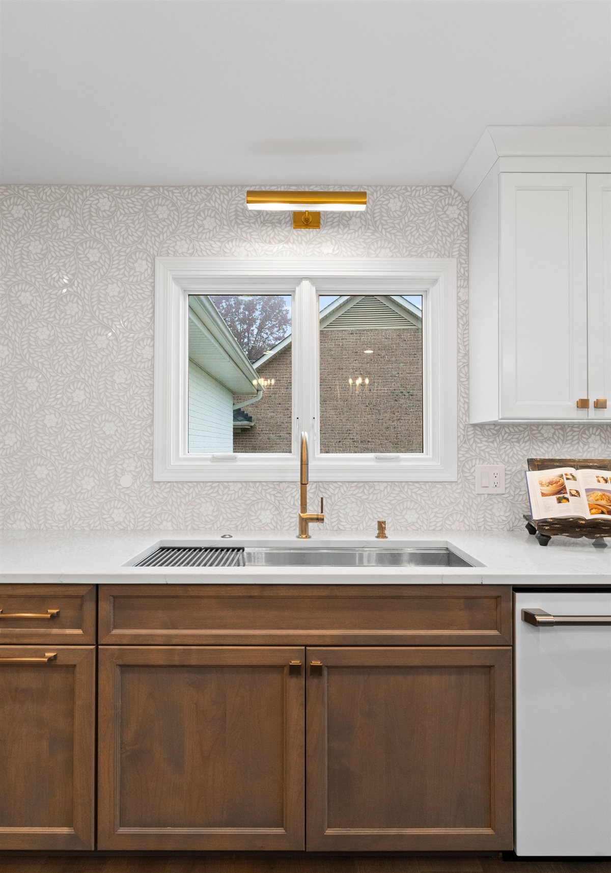 Sink wall with wood cabinetry and a brass sconce, River Chase kitchen
