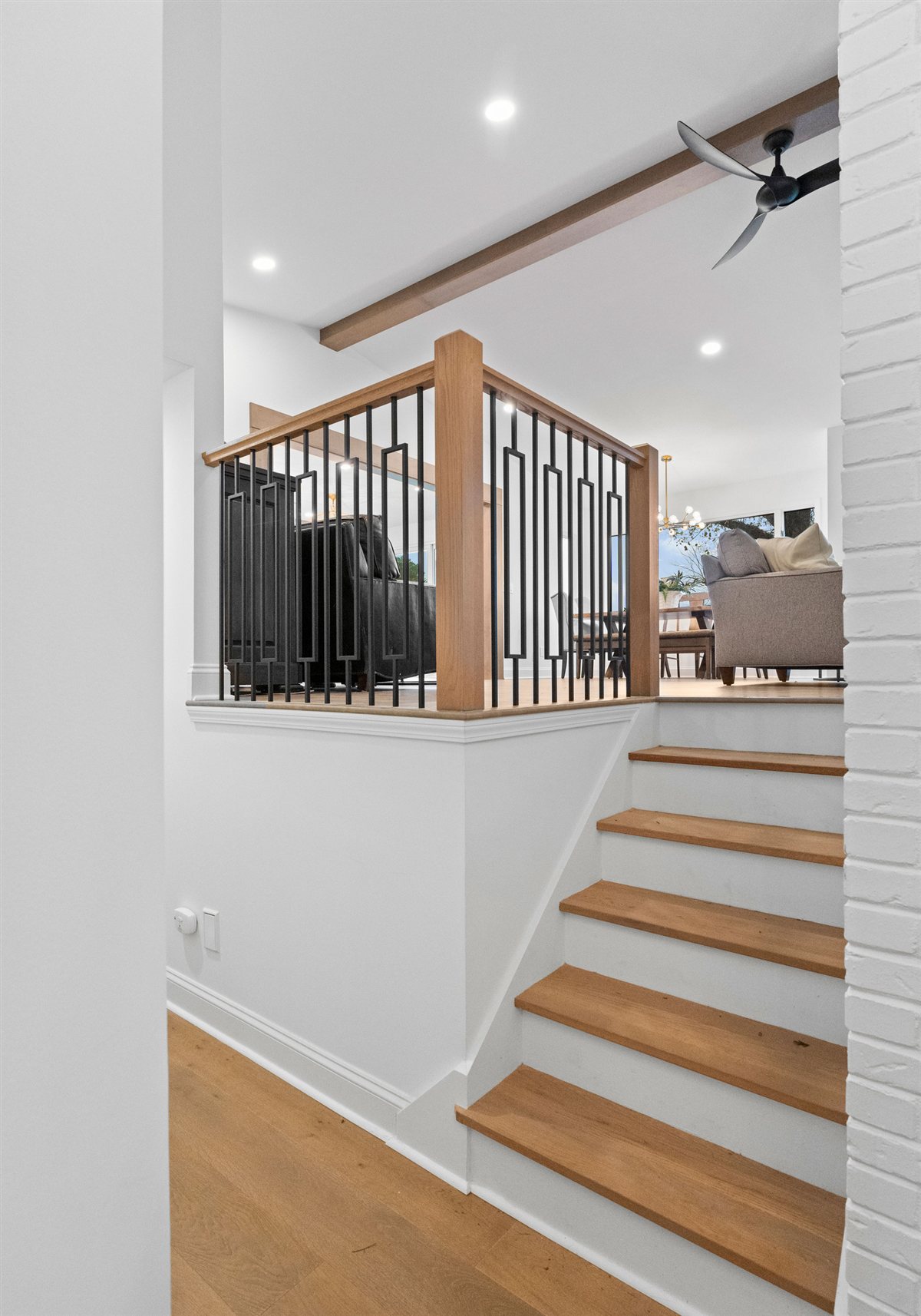 Oak stair treads rising to a railing with black balusters, River Chase renovation