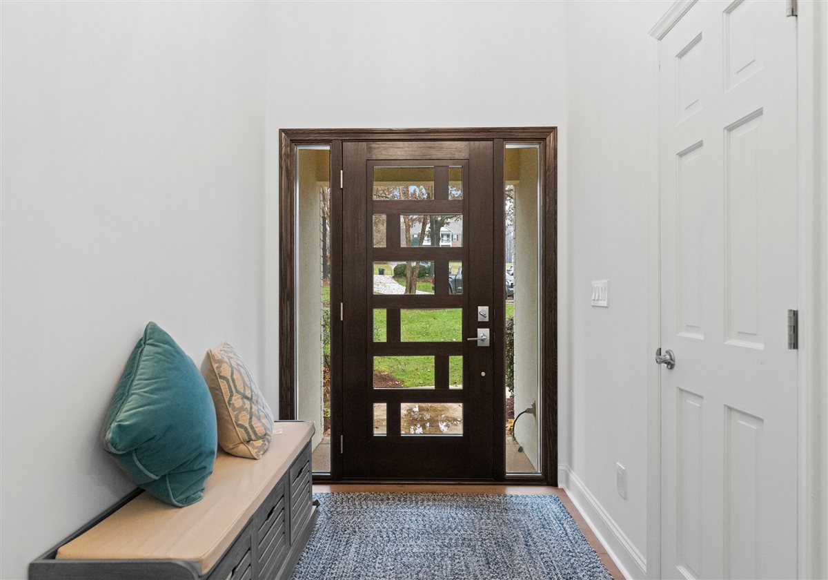 Entry hall with a modern glass-panel front door and a bench, River Chase renovation
