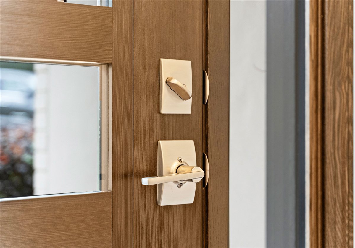 Wood front door detail with brass lever hardware, River Chase renovation