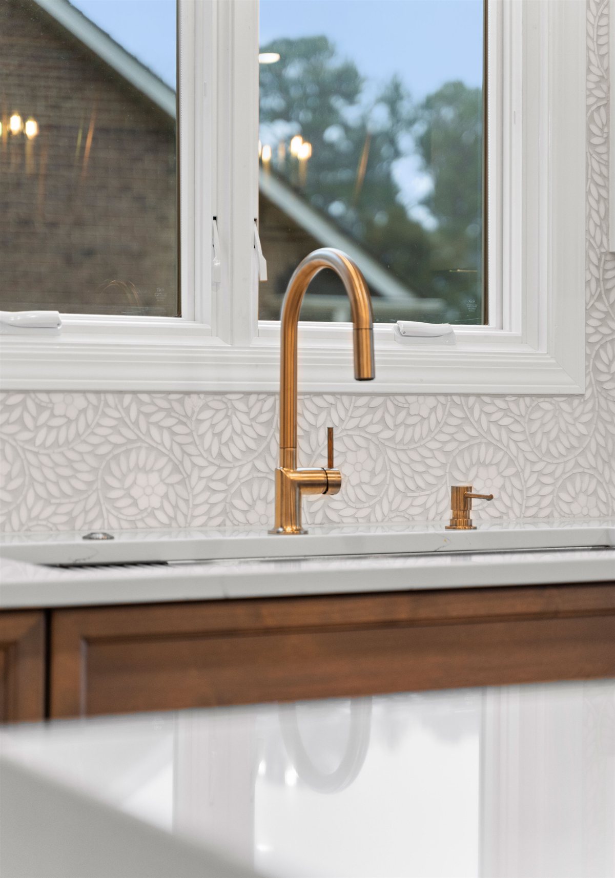 Brass faucet at a window with a patterned tile backsplash, River Chase kitchen
