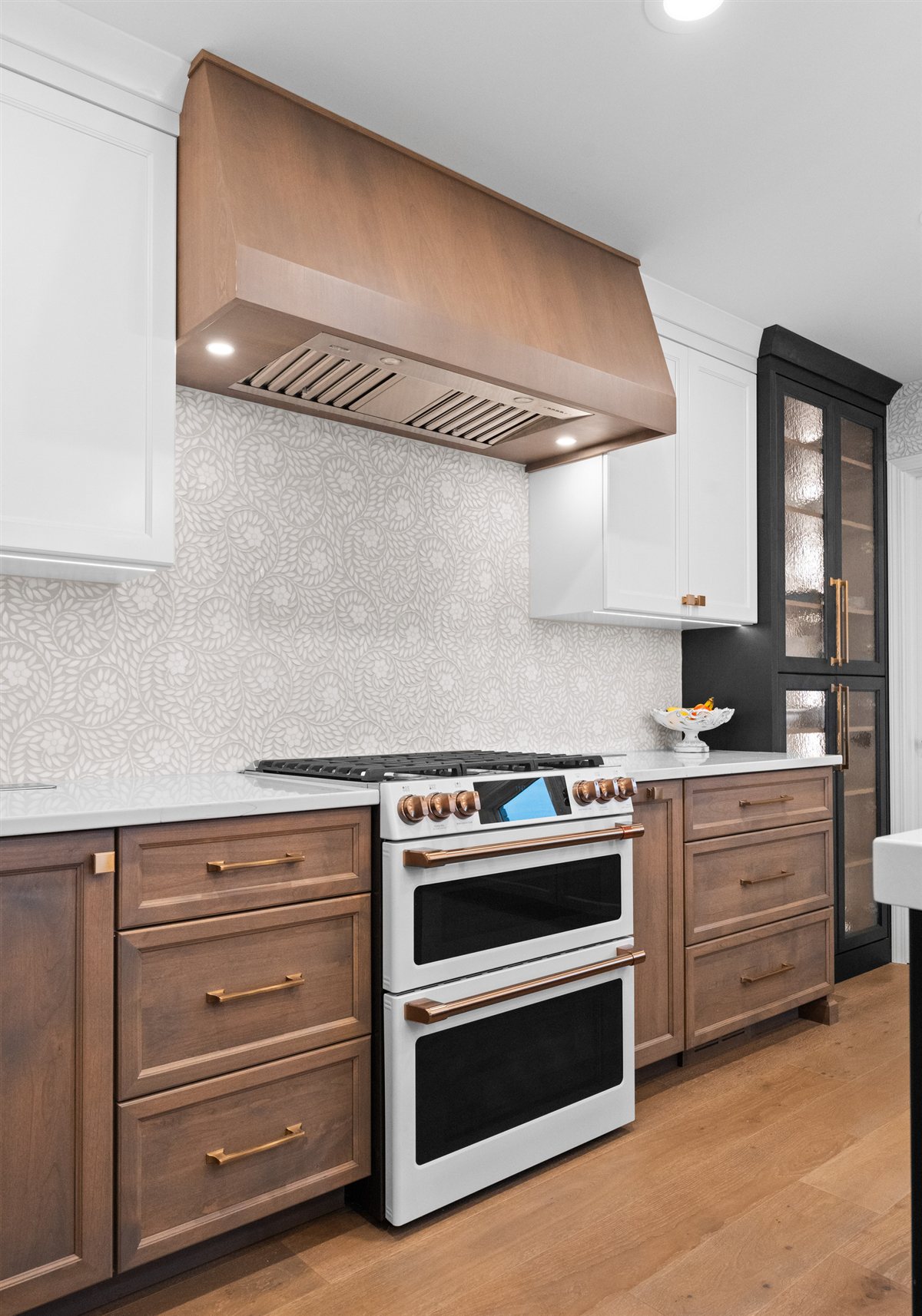 Range wall with a wood-clad hood and white double oven, River Chase kitchen