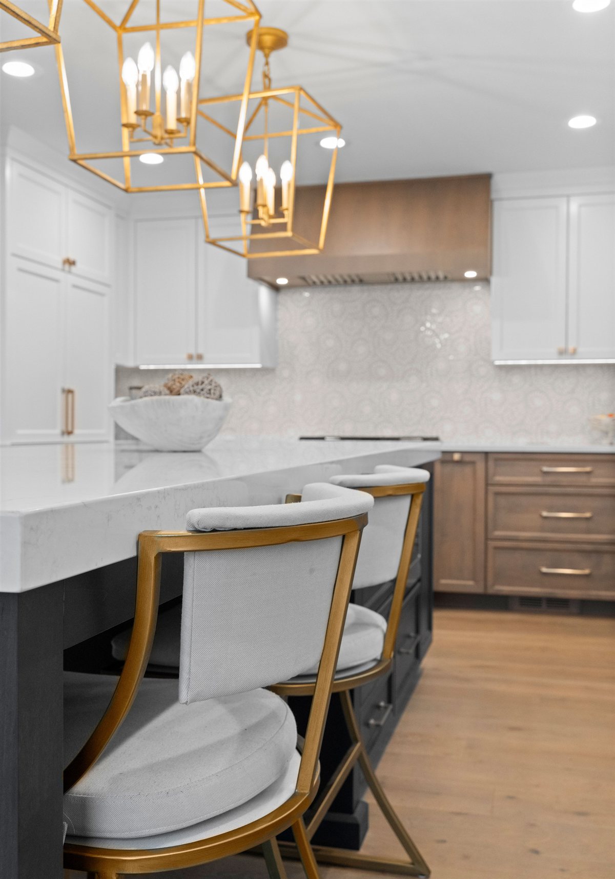 Island seating with upholstered stools under brass pendants, River Chase kitchen