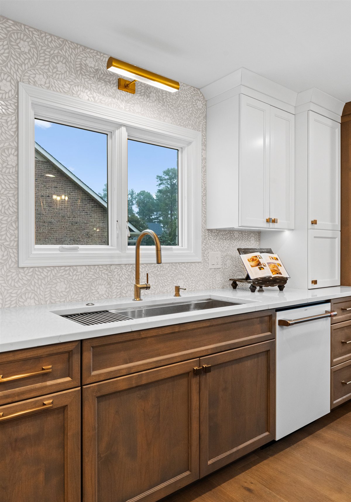 Sink under a window with wood base cabinets and patterned tile, River Chase kitchen