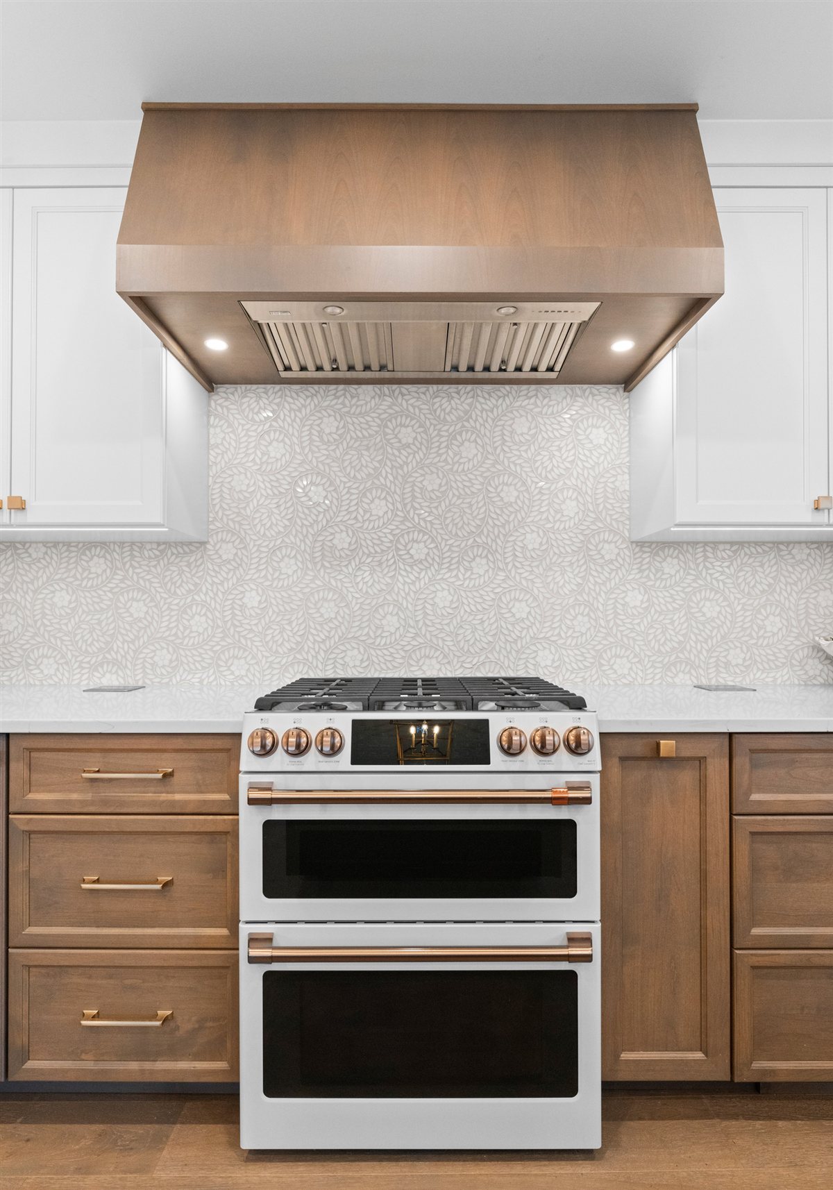 White range with copper hardware under a wood hood, River Chase kitchen