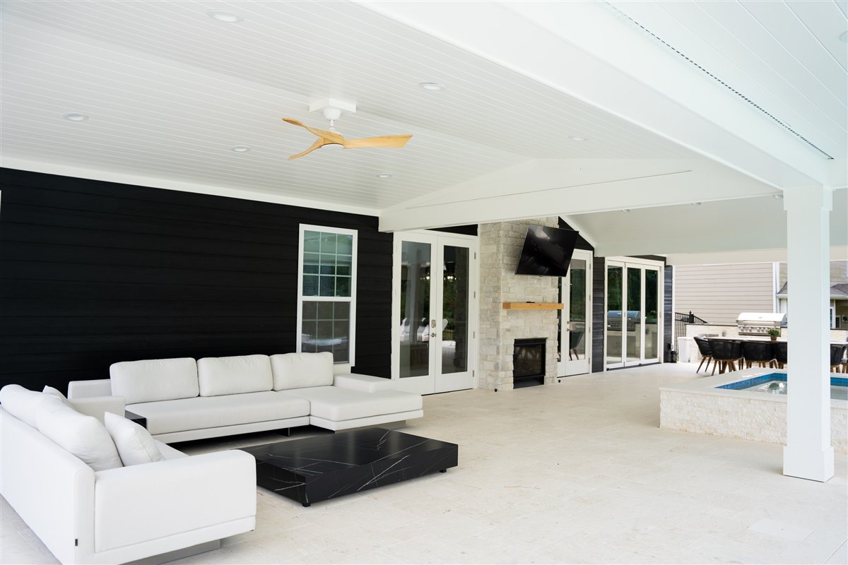 Outdoor living room with white sofas and a stone fireplace, Denver outdoor living