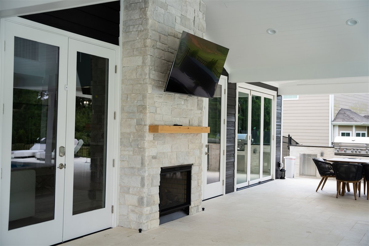 Stone fireplace with a mounted television beside French doors, Denver outdoor living