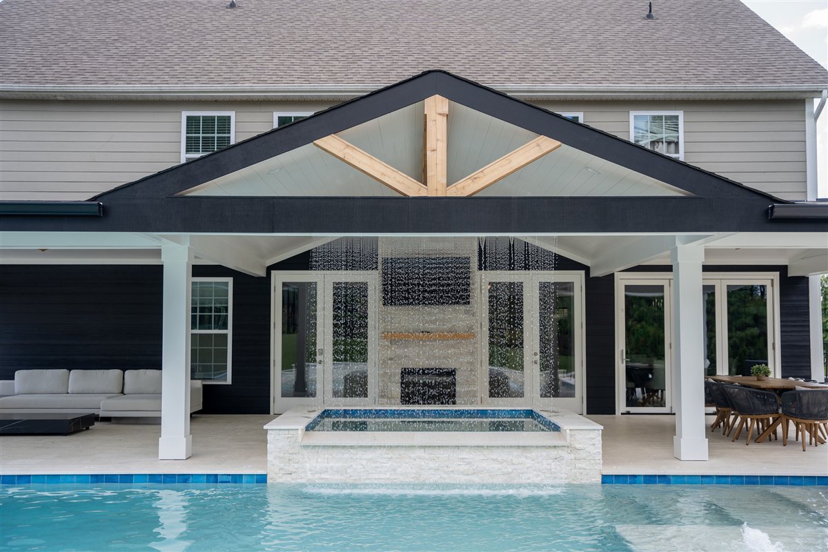 Covered porch with a stone fireplace behind the pool and spa, Denver outdoor living