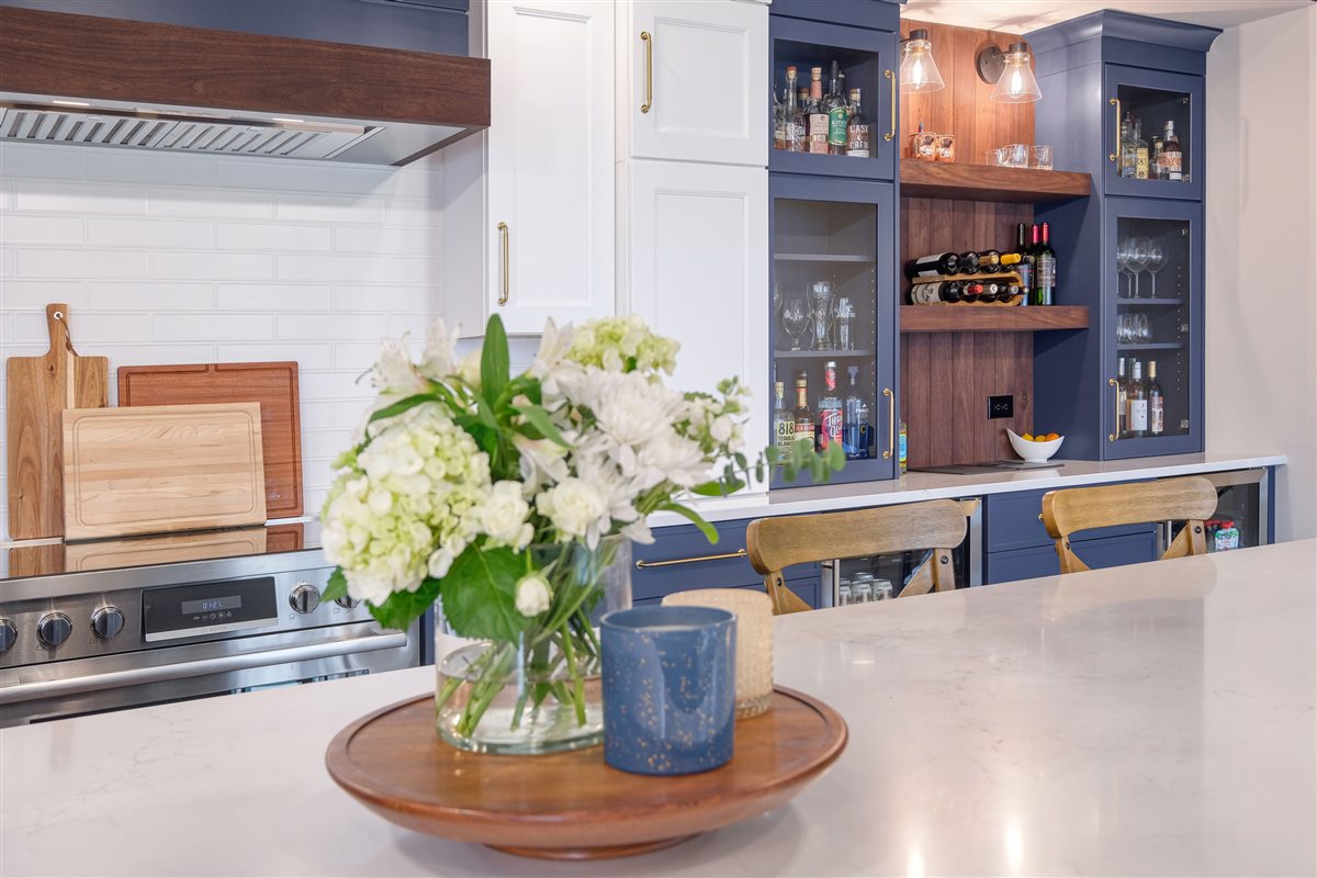 Flower arrangement on the island with a wood hood beyond, Moss Lake kitchen
