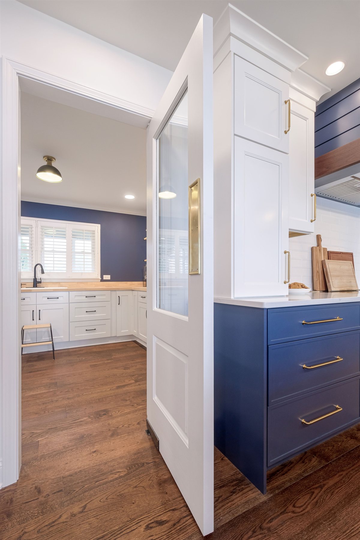 Paneled pantry door open beside blue cabinetry, Moss Lake kitchen