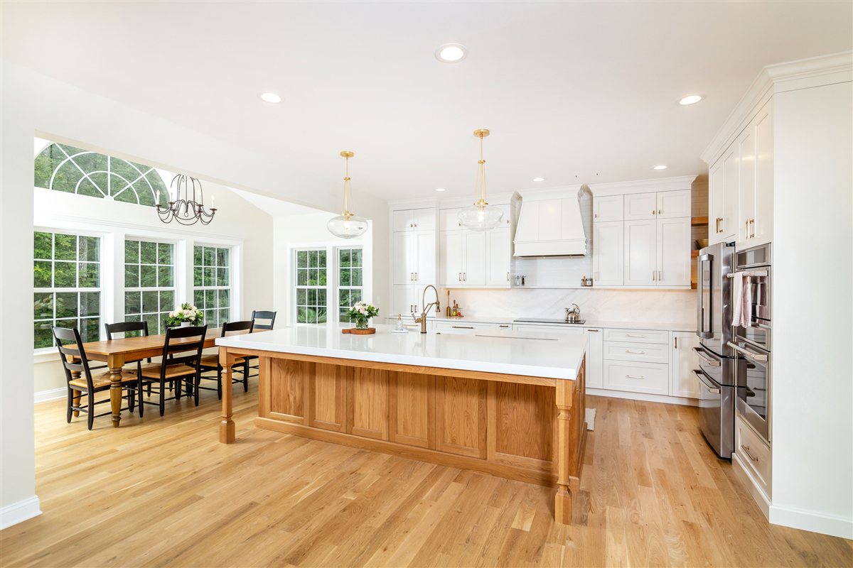 Open kitchen with a natural wood island and a dining table by arched windows, Monroe kitchen renovation