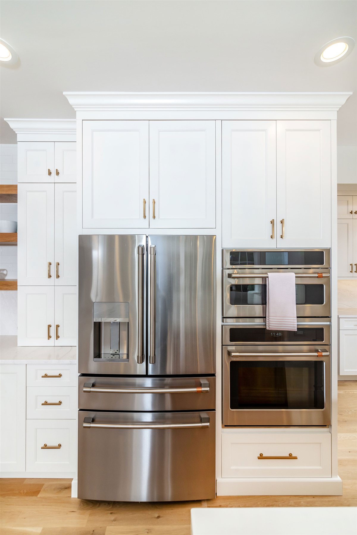 Refrigerator and wall ovens beside open wood shelves, Monroe kitchen