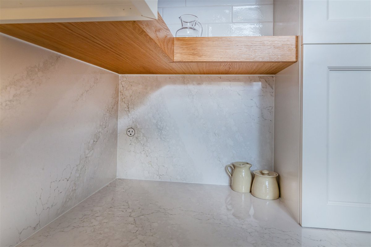 Stone backsplash beneath a wood floating shelf, Monroe kitchen