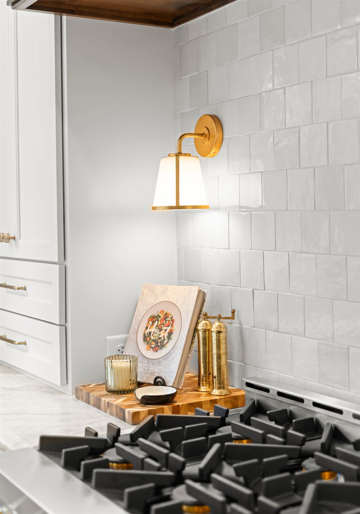 Gas range with a brass sconce and white tile, The Point whole-home renovation in Mooresville