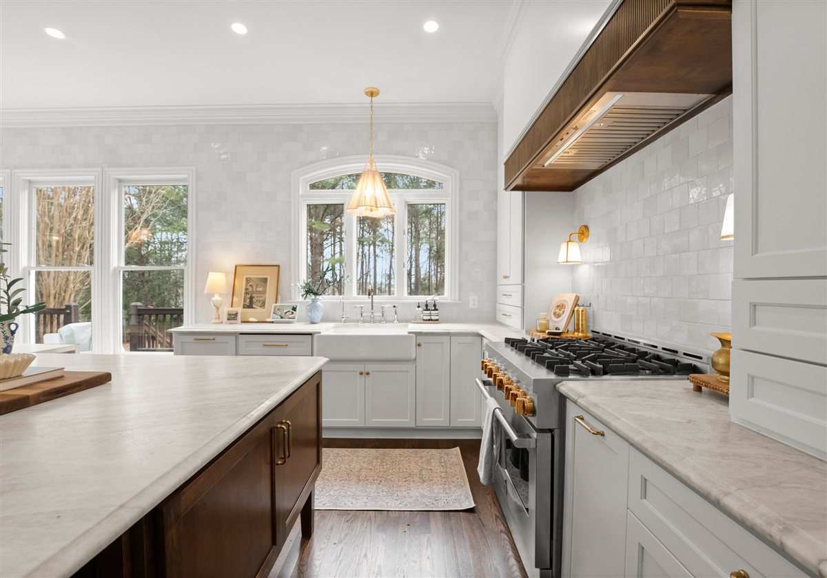 Kitchen with a wood range hood, brass accents and windows over the sink, The Point renovation