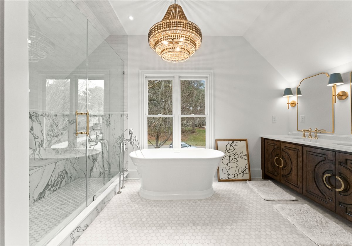Primary bath with a freestanding tub, deck-mounted filler, specialty-built vanity and gold chandelier, The Point renovation