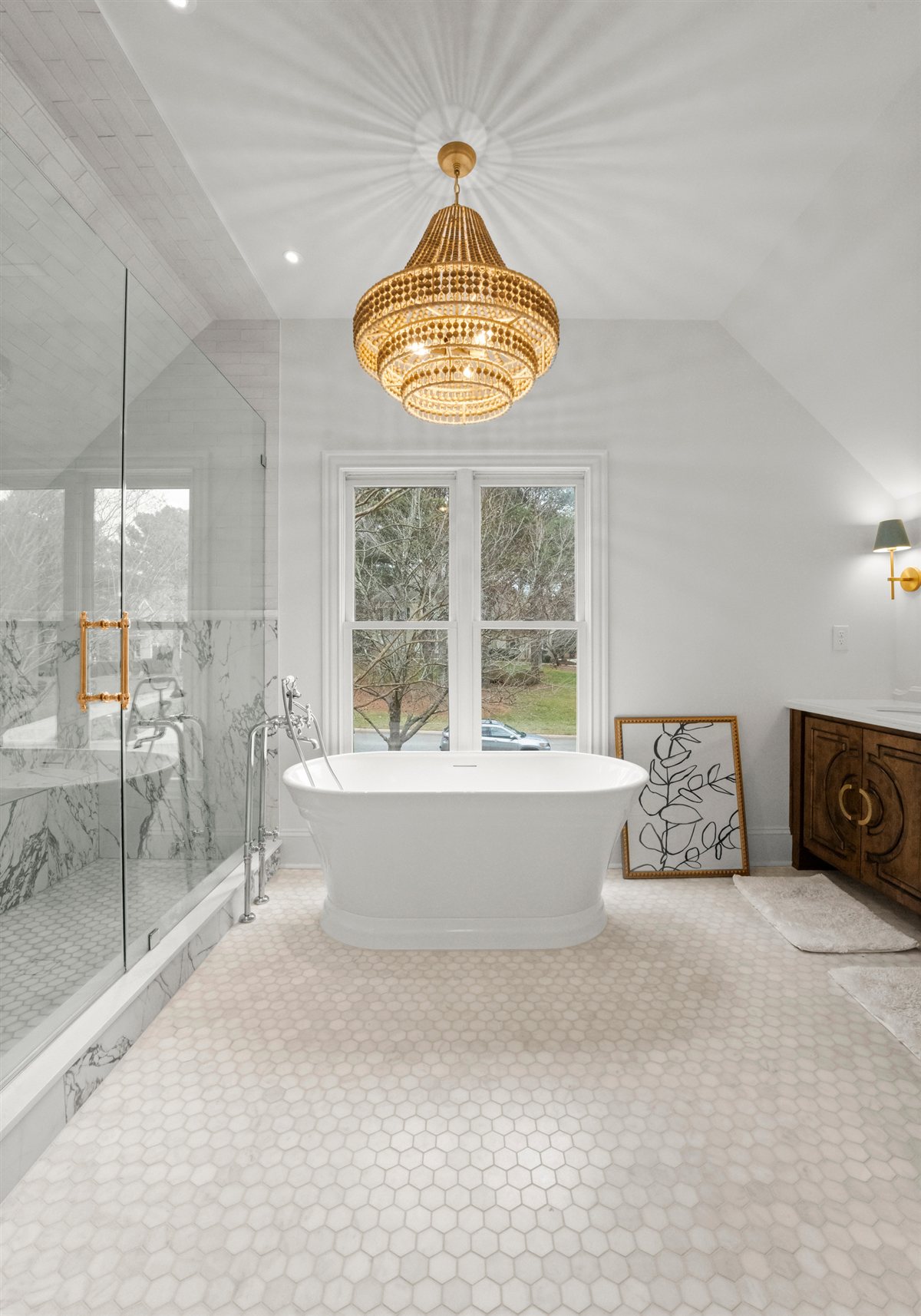 Primary bath with a freestanding tub under a gold chandelier, The Point renovation