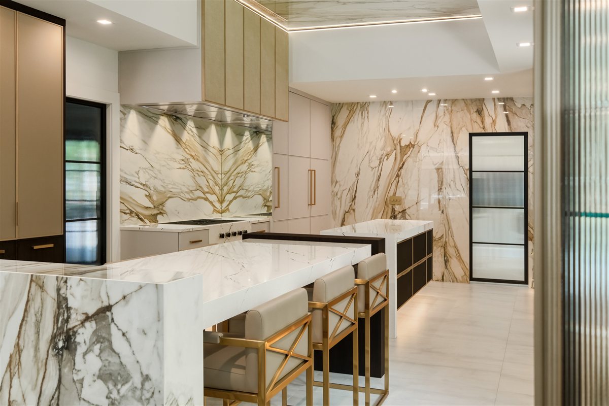 Kitchen with porcelain slab walls, brass stools and a quartz waterfall island, Pellyn Wood renovation