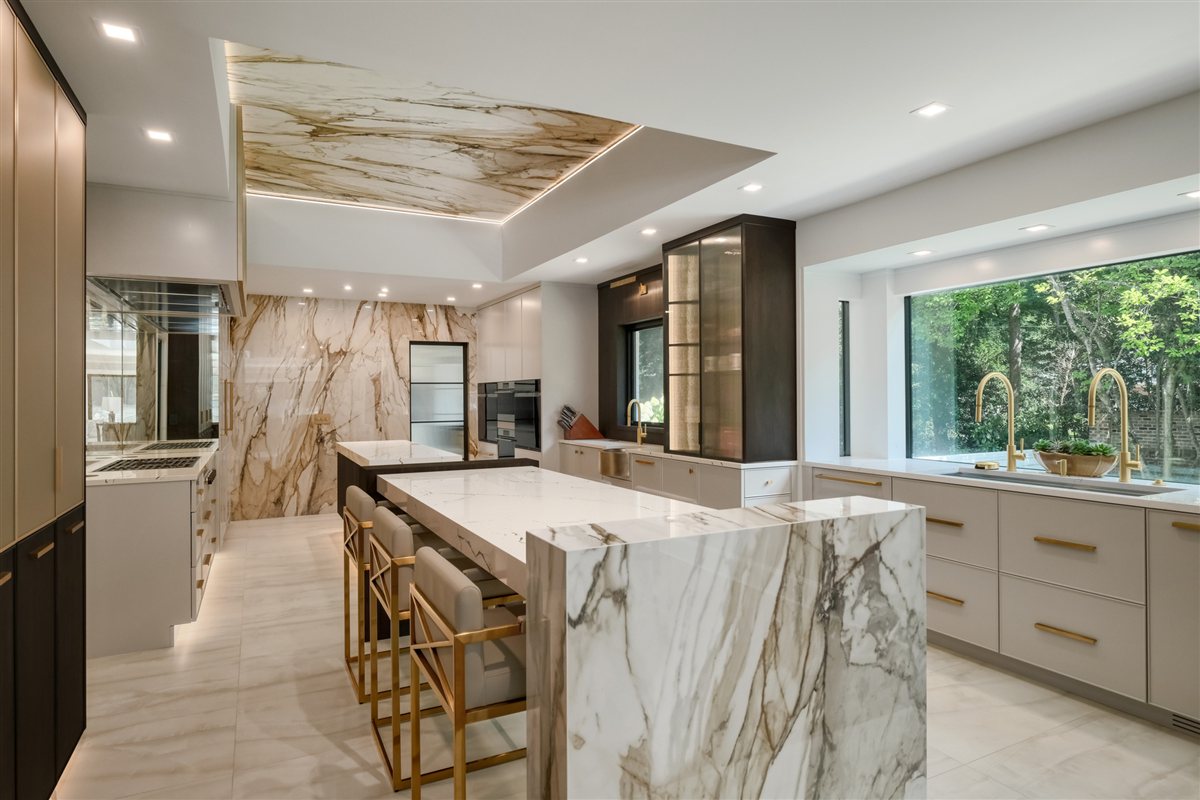 Kitchen with a mitered quartz waterfall island and jumbo porcelain slab walls, Pellyn Wood renovation