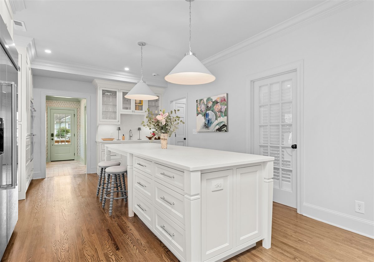 White kitchen with an island and pendants toward the mudroom, Providence Park historic home