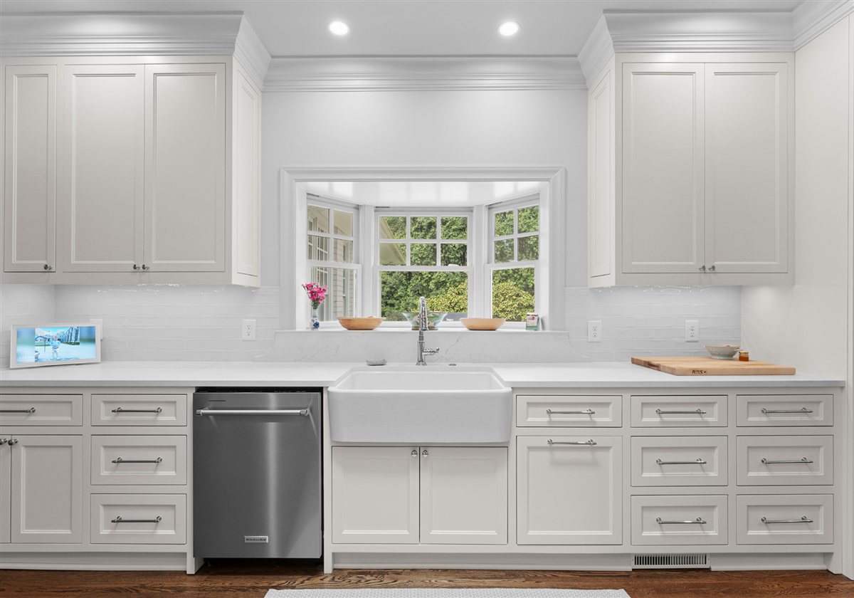 Farmhouse sink under a window with white cabinetry, Providence Park historic home