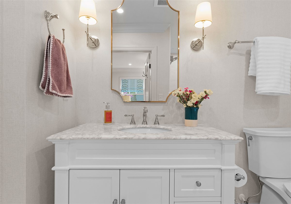 Bath vanity with brass sconces and a gold mirror, Providence Park historic home