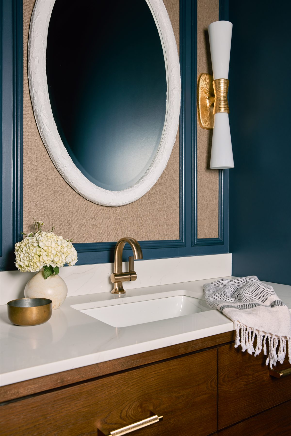 Powder bath detail: oval mirror, brass faucet and textured wallcovering in navy molding, Charlotte renovation