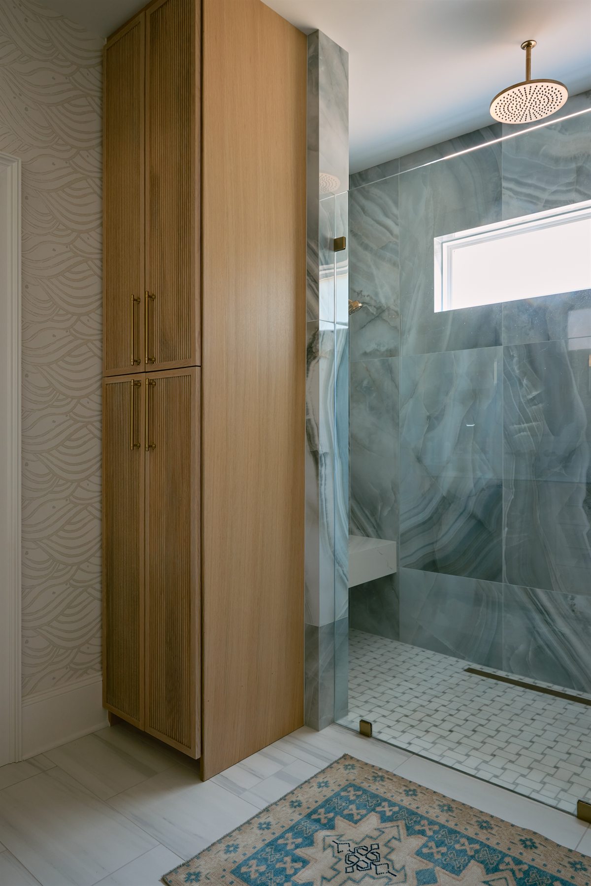 Curbless shower in blue-gray veined tile beside a tall wood linen cabinet, Providence Springs primary bath, Charlotte