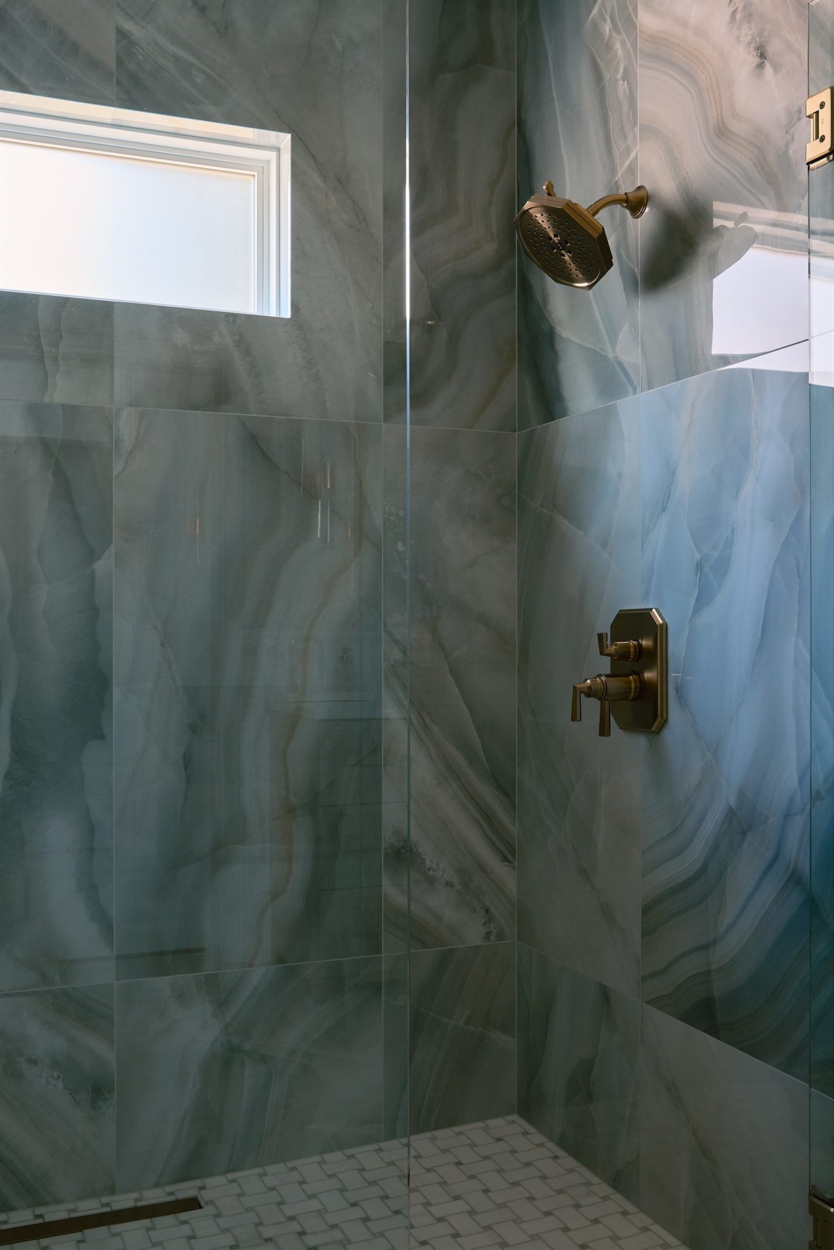 Curbless walk-in shower with large-format blue-gray tile, brass fixtures and a new window, Charlotte primary bath remodel