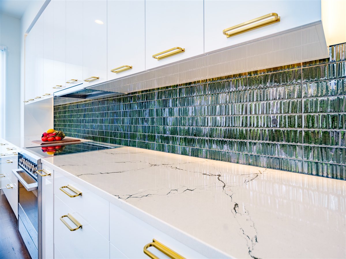 Veined countertop with brass pulls and green tile, SouthPark kitchen