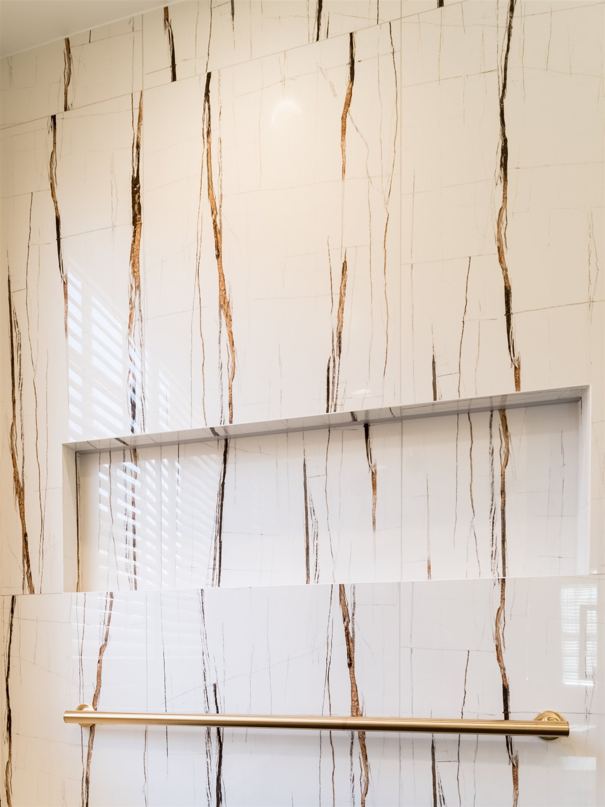 Veined shower wall with brass fixtures, SouthPark renovation