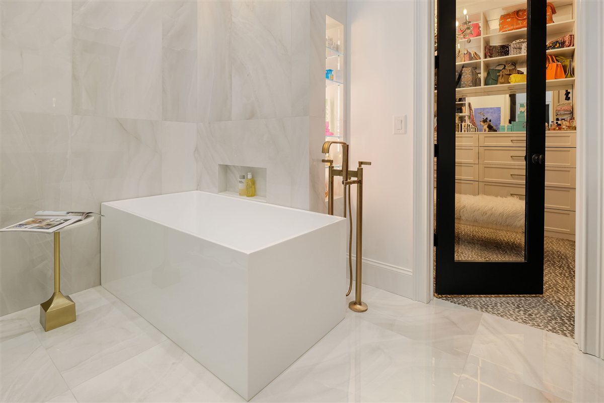Primary bath with a freestanding tub, brass floor-mounted filler and white veined walls, Uptown Charlotte primary suite renovation