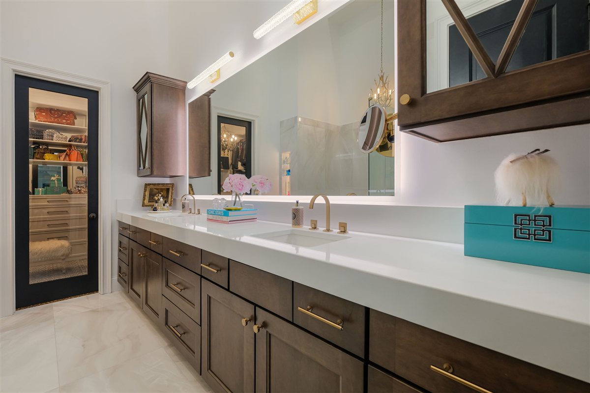 Double vanity with dark wood cabinetry and a lit mirror, Uptown primary suite